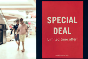 Two men walking past a Special Deal promo sign