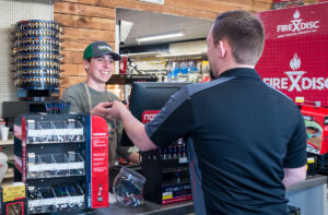 Image of a smiling store clerk ringing up a customer purchase.