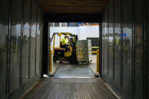 A forklift removing a pallet of stock from a delivery truck.