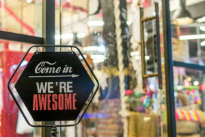 A "Come In. We're Awesome" sign outside a retail store.