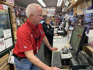A hardware store manager working on a checkout stand terminal.