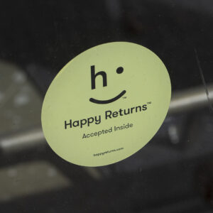 A sign reading Happy Returns on a retail store's door.
