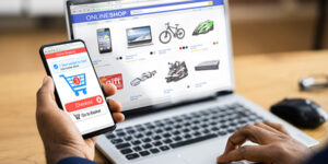 An image of a man making an online purchase with his laptop and phone.