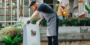 Image of a store owner placing a sandwich board sign in front of his business