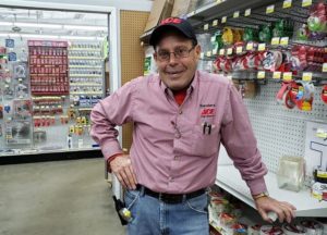 Smiling older gentleman leans on retail shelf in hardware store
