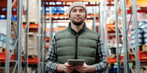 Man standing in warehouse holding electronic tablet