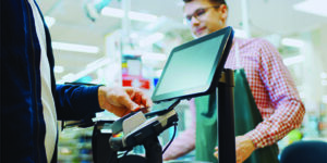 Image of a man paying for a purchase with his phone at a point of sale.
