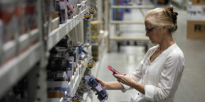 A woman scanning a product's QR code in a hardware store aisle.
