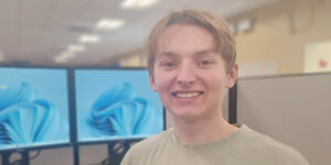 Paladin TSR Cade Malkin in front of a pair of computer monitors in his Paladin Support cubicle.